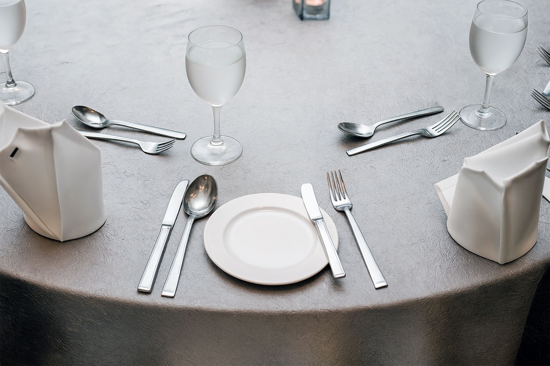 Formal table setting with a white plate, silverware, and water glasses.