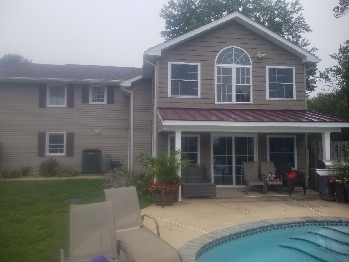 Backyard with two-story house, patio furniture, and swimming pool under cloudy sky