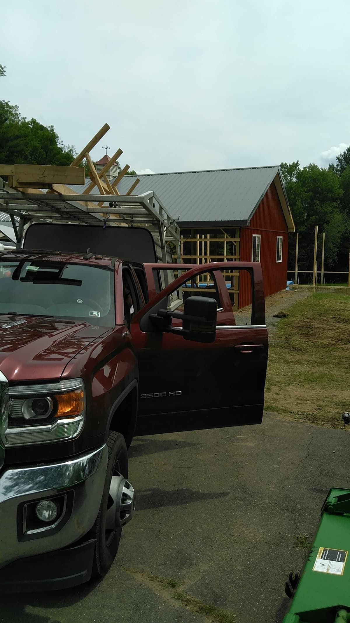 Red pickup truck with open door parked beside a red house after storm damage, broken roof visible