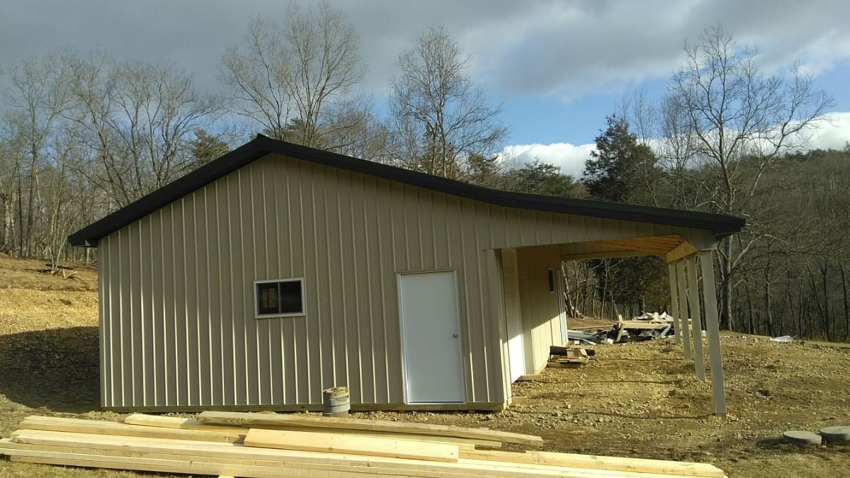 Small beige metal shed with white door on a rural lot under cloudy sky