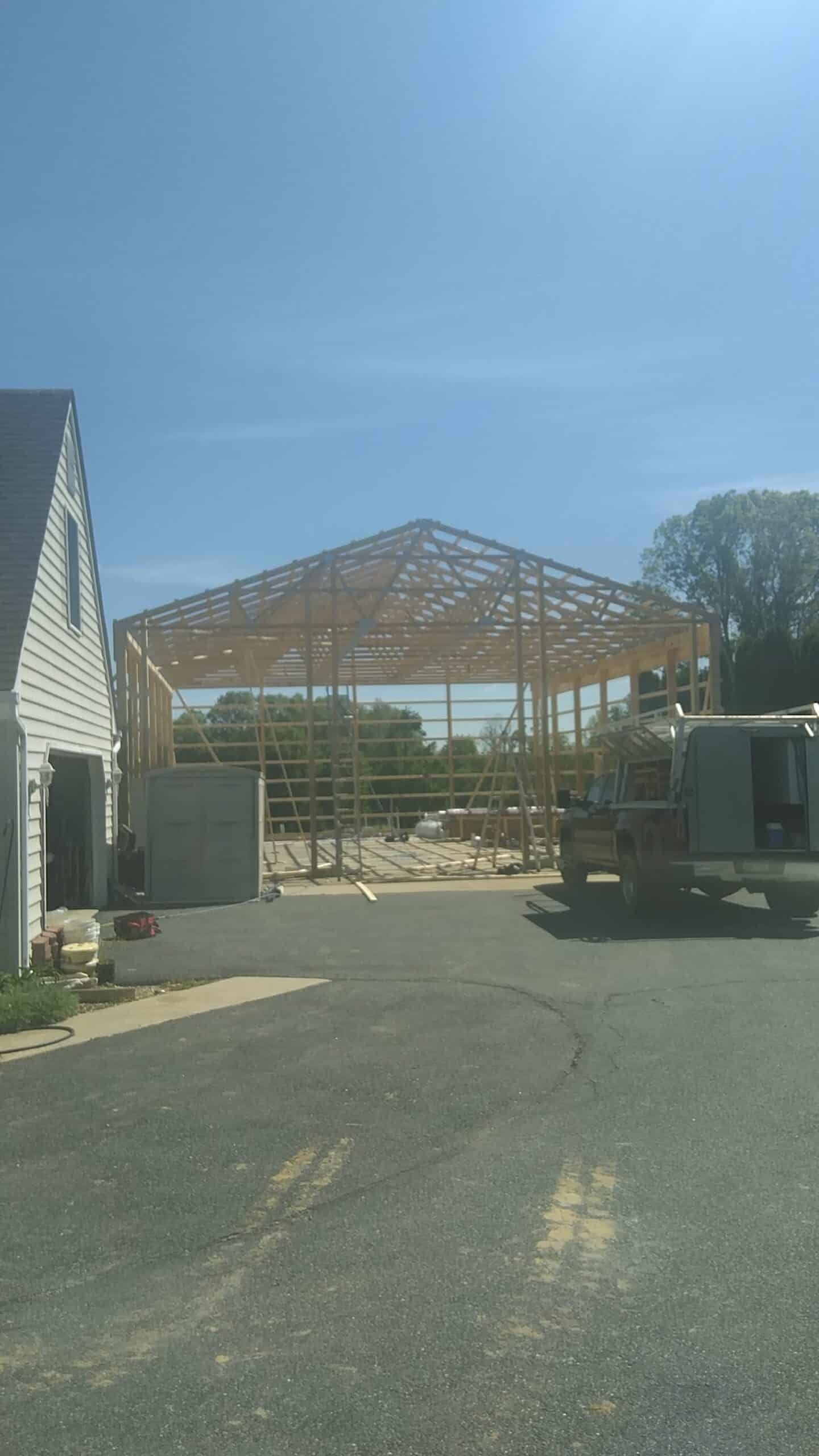 Construction site with a large wooden roof frame between buildings under a clear blue sky
