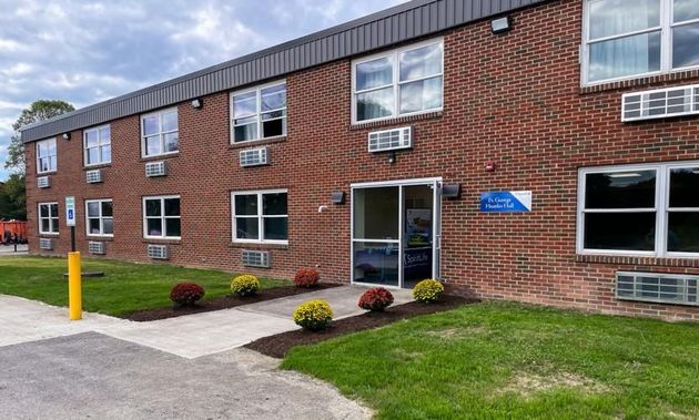 A group of people sitting in a circle applauding a person standing in the center within a bright, professional office.
