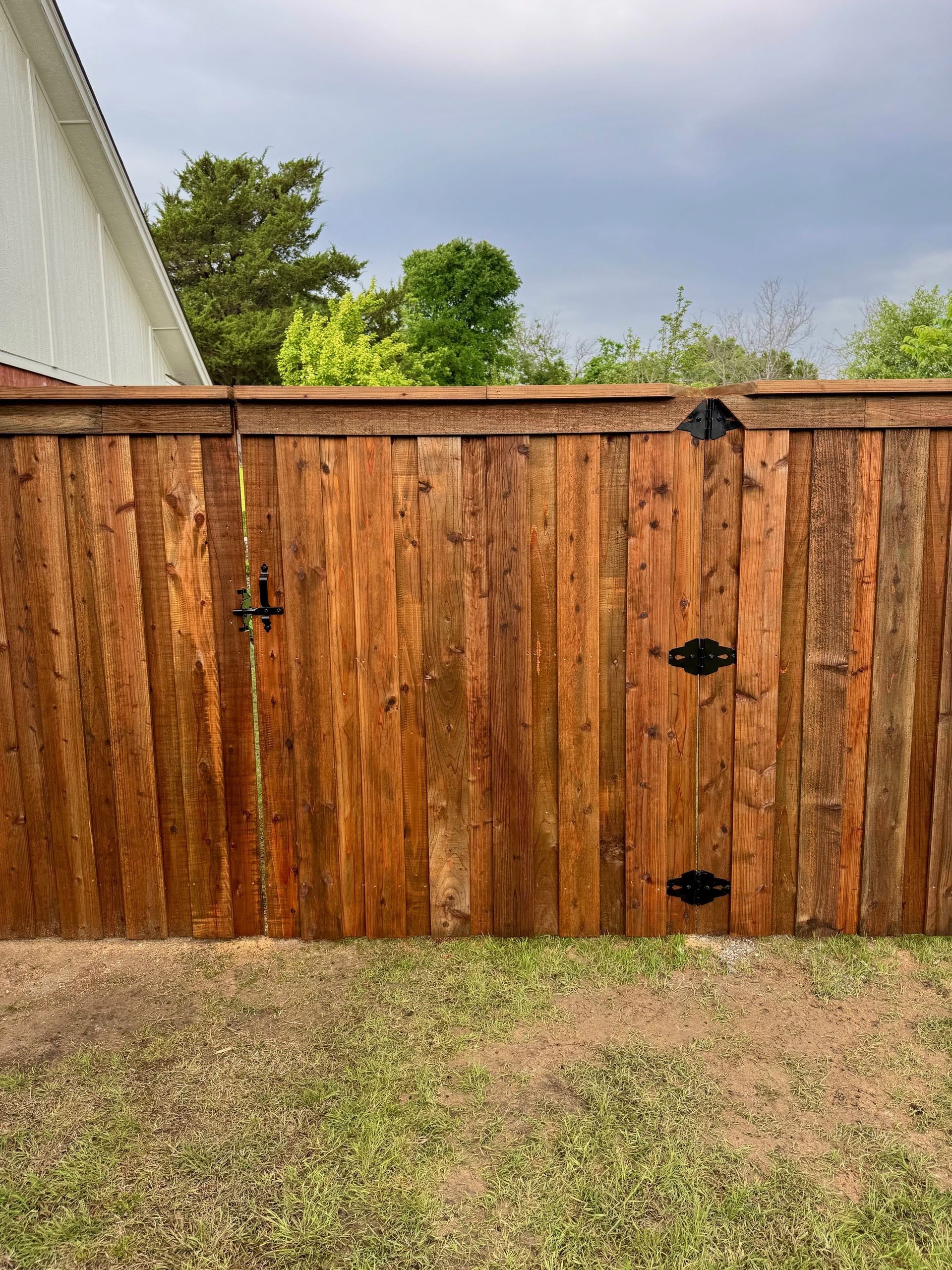 A wooden fence with a gate in the backyard of a house.