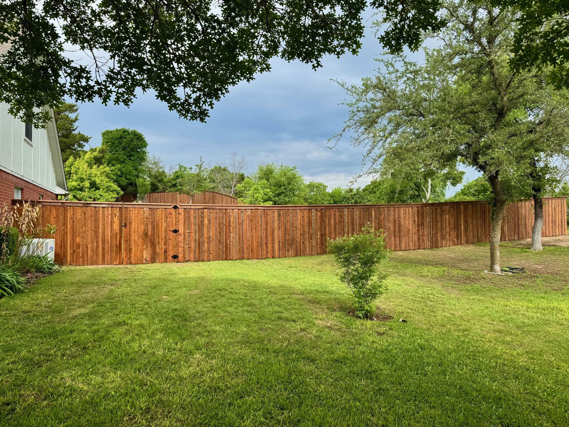 A wooden fence surrounds a lush green yard.