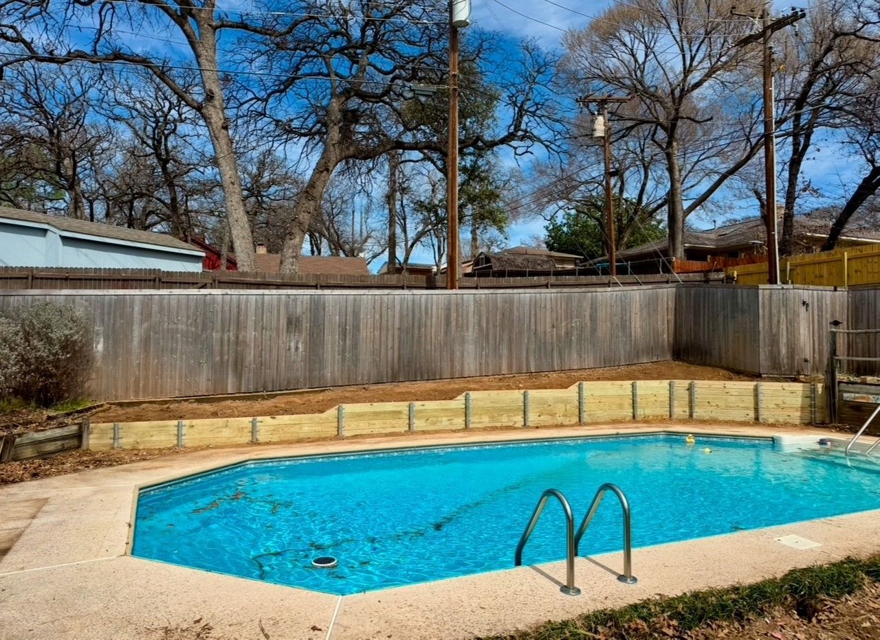 A large swimming pool with a wooden fence surrounding it.