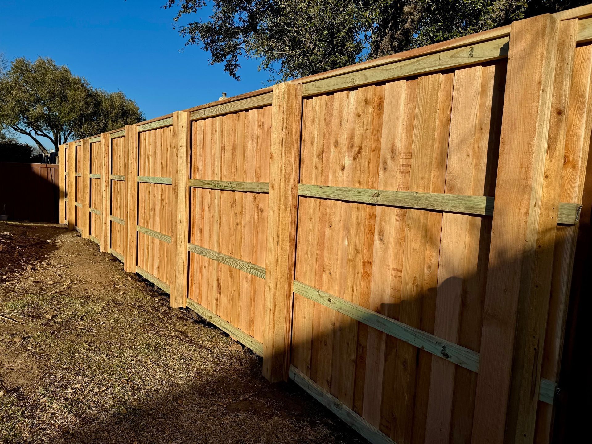 A wooden fence is sitting in the middle of a dirt field.