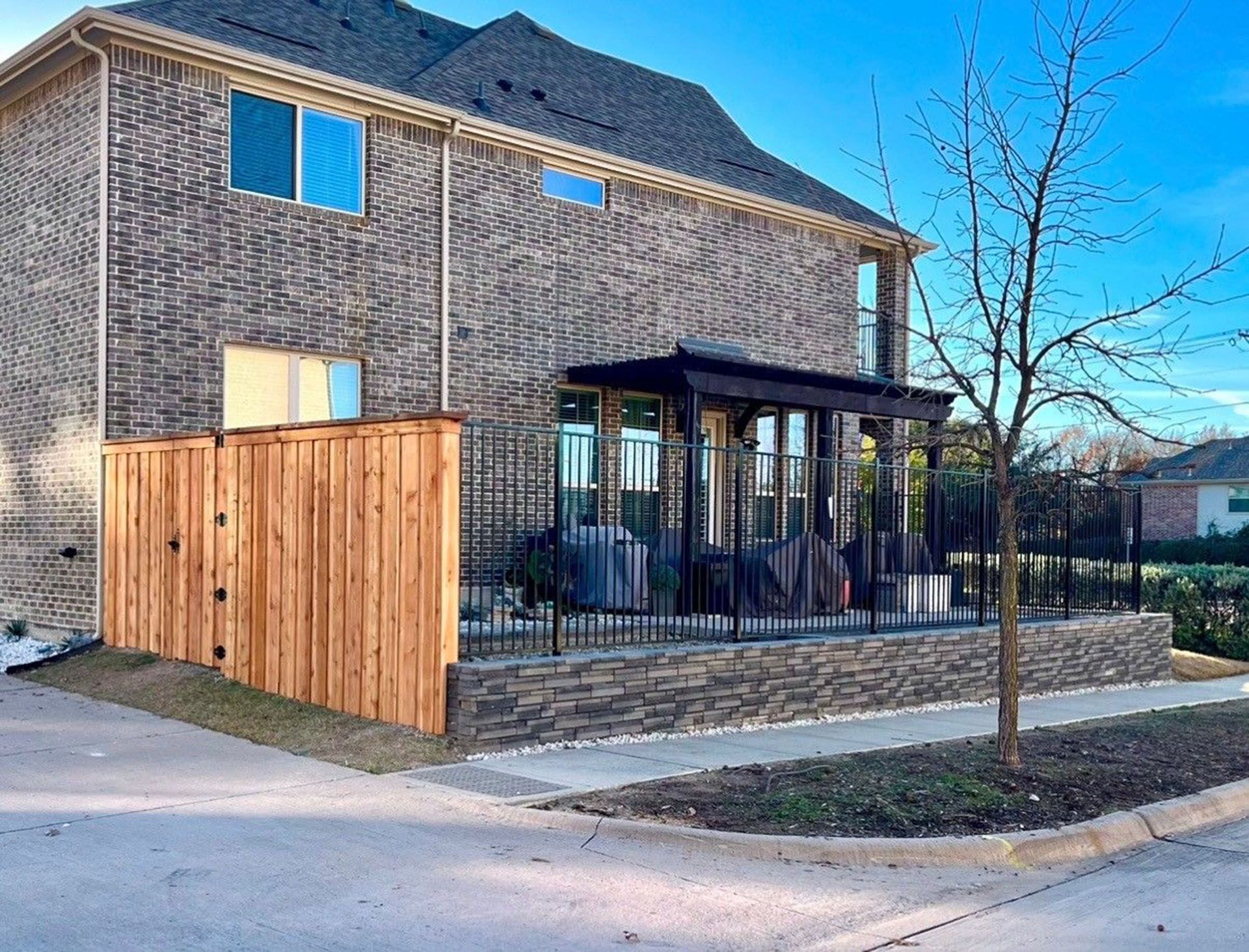 A large brick house with a wooden fence in front of it.