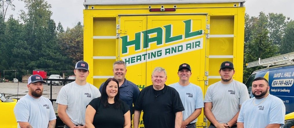 Group of people posing in front of a yellow truck with company logo