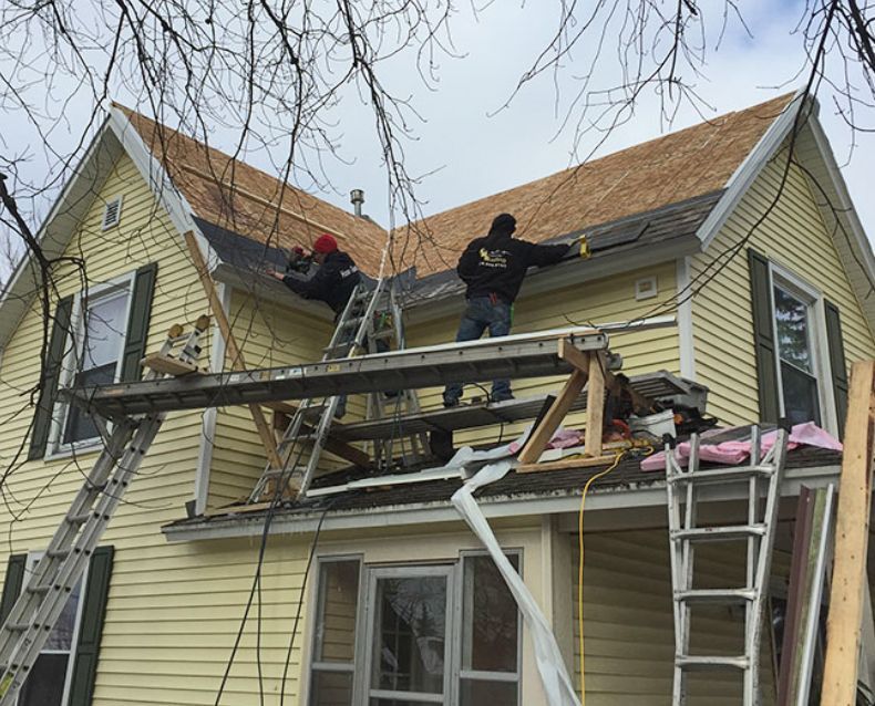 A couple of men are working on the roof of a house.