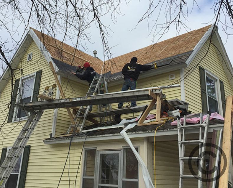 A couple of men are working on the roof of a house.