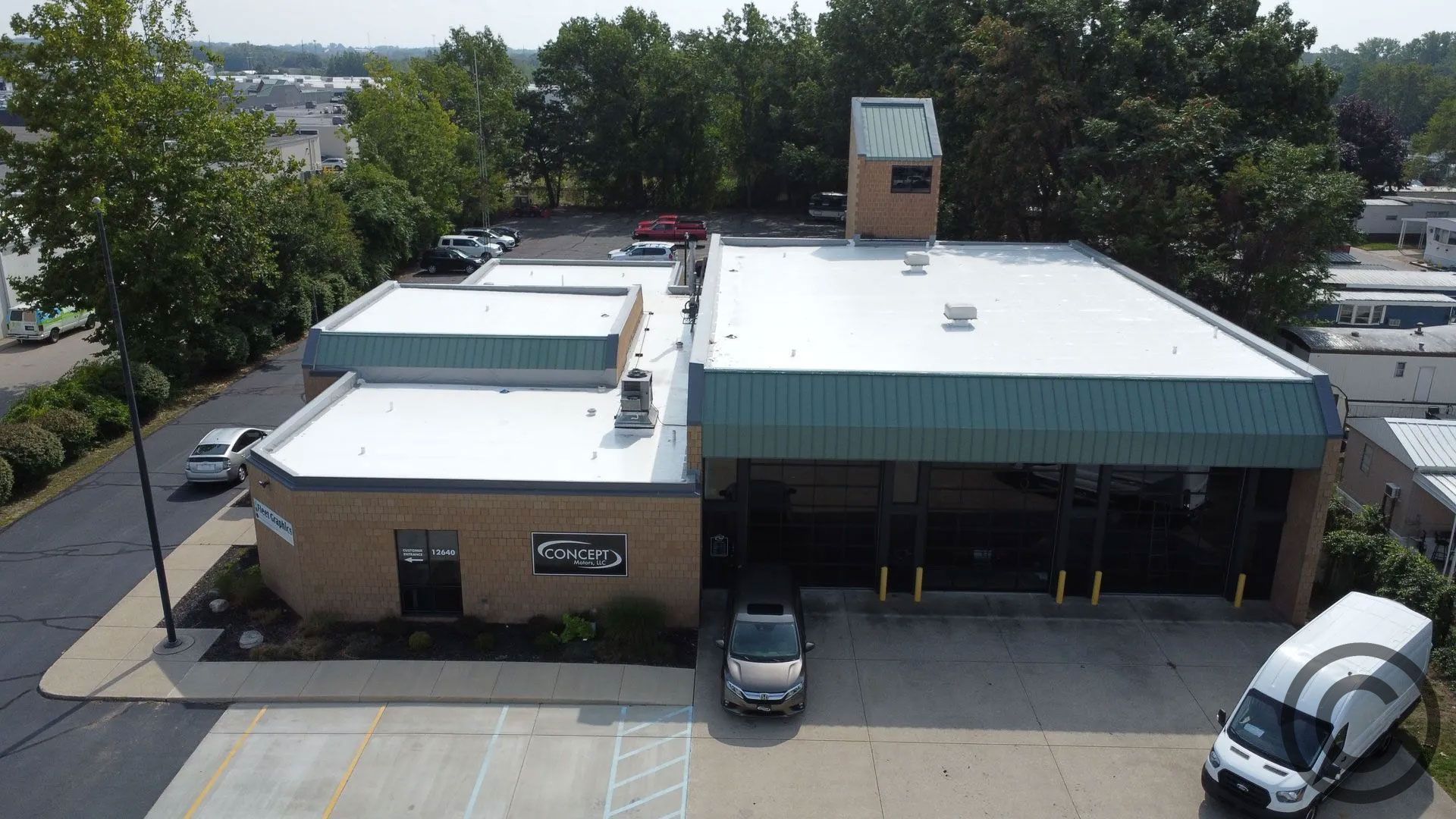 Aerial view of a commercial building with a light-colored brick exterior, with a van parked in front.