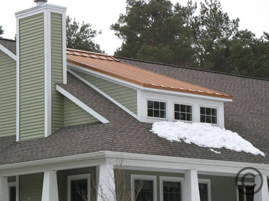 House with green siding and a copper roof, snow on the roof.
