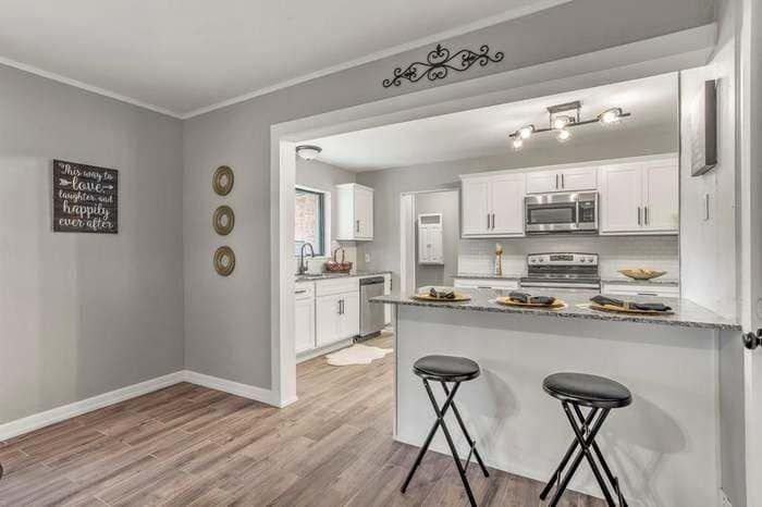 A kitchen with a bar and stools in a house.