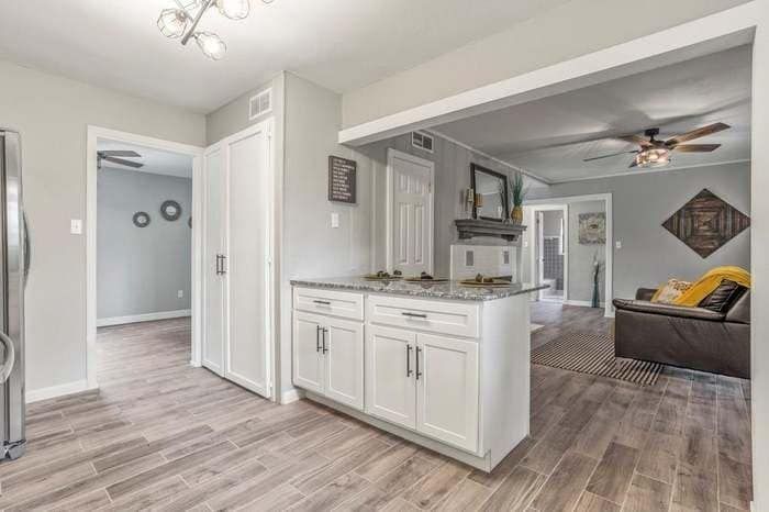 A kitchen with white cabinets and a stainless steel refrigerator.