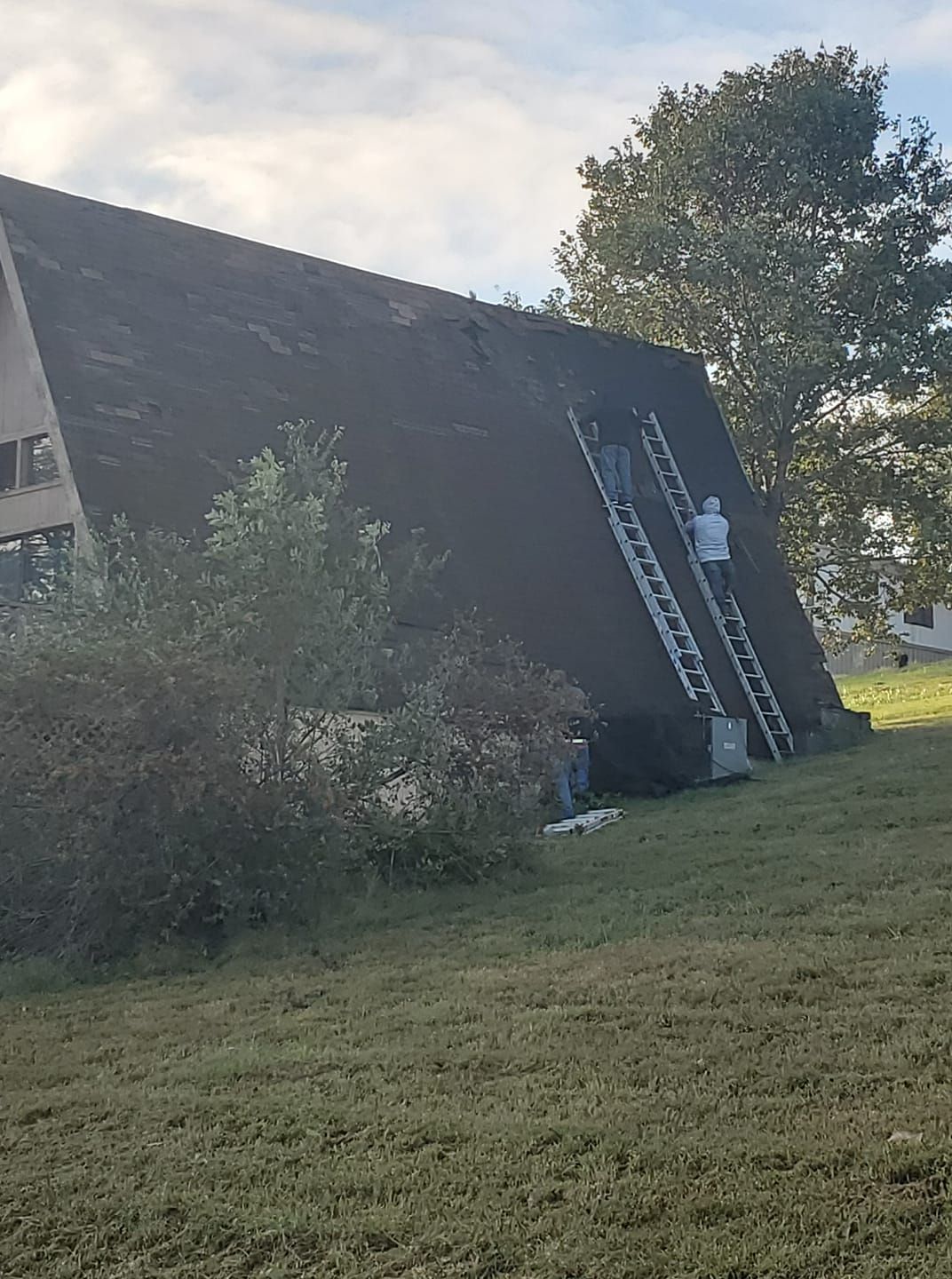 A man is standing on a ladder on the side of a building.