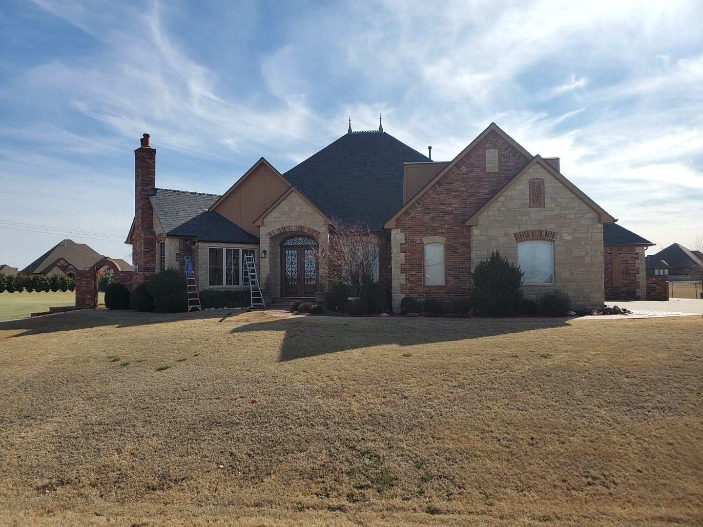 A large brick house is sitting on top of a dirt field.