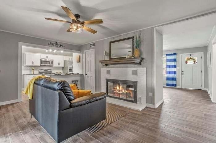 A living room with a fireplace and a ceiling fan.