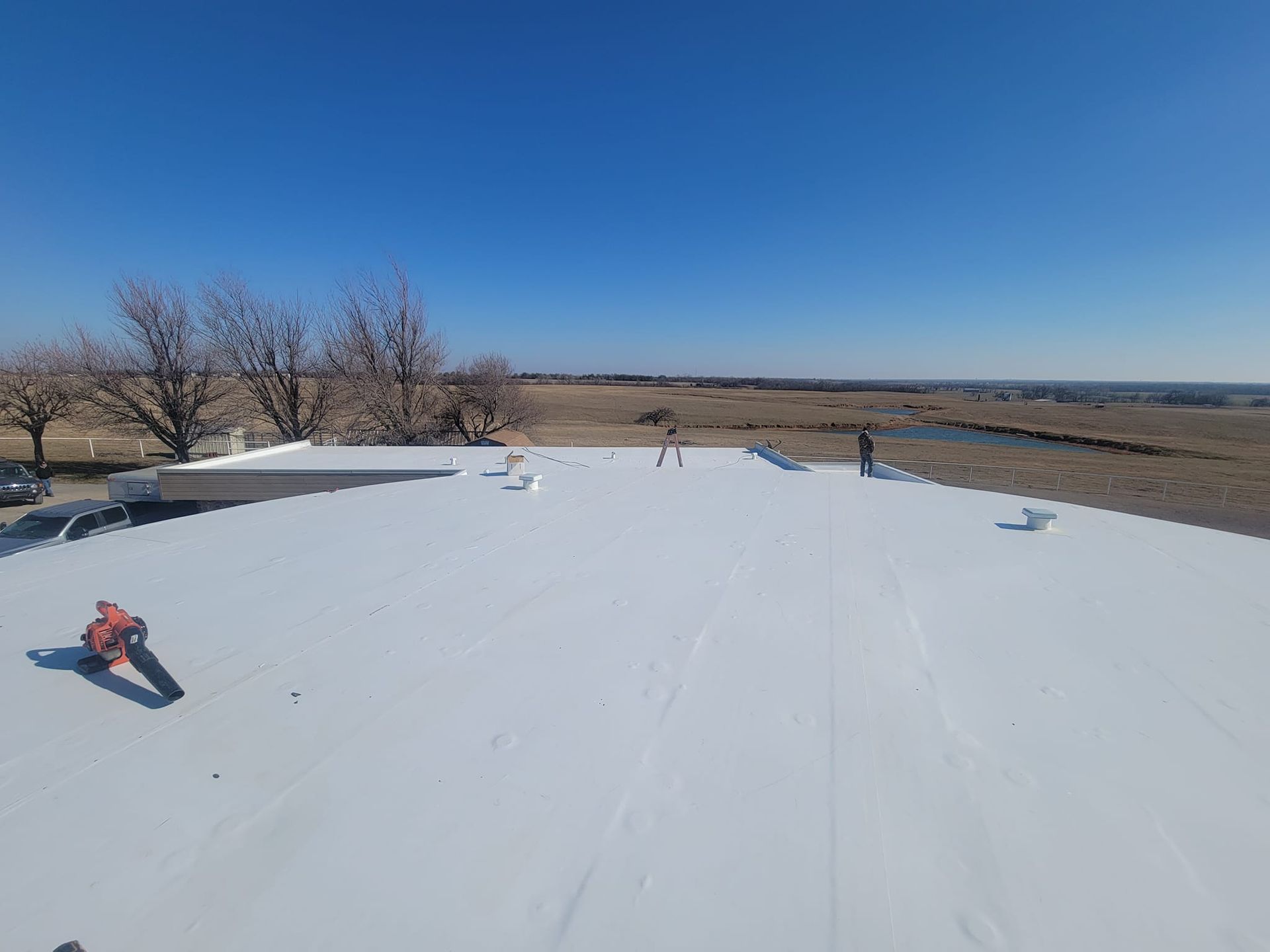 A man is standing on top of a white roof.