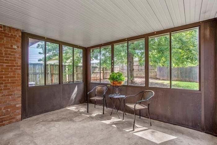 A screened in porch with chairs and a table.