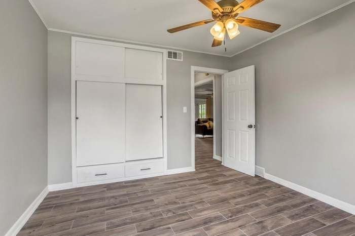 A bedroom with a ceiling fan and sliding doors.