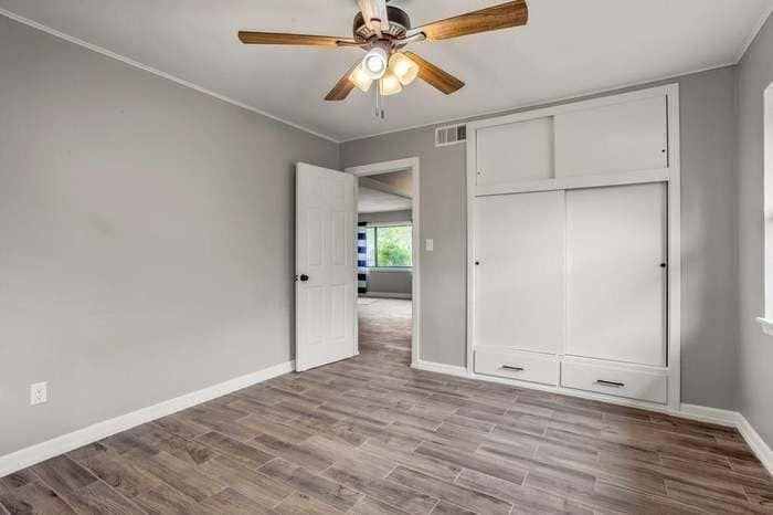 An empty bedroom with hardwood floors and a ceiling fan.