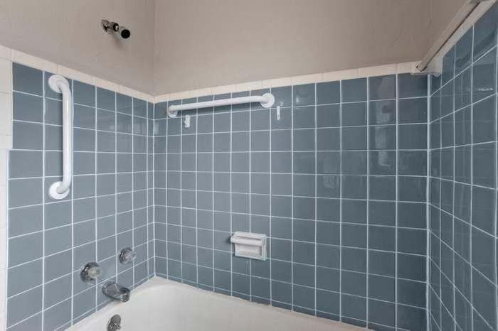 A bathroom with blue tile walls and a bathtub.