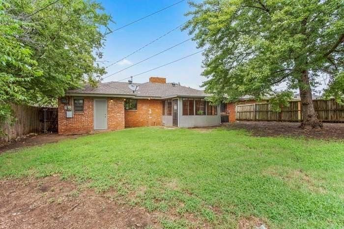 A brick house with a large lawn in front of it.