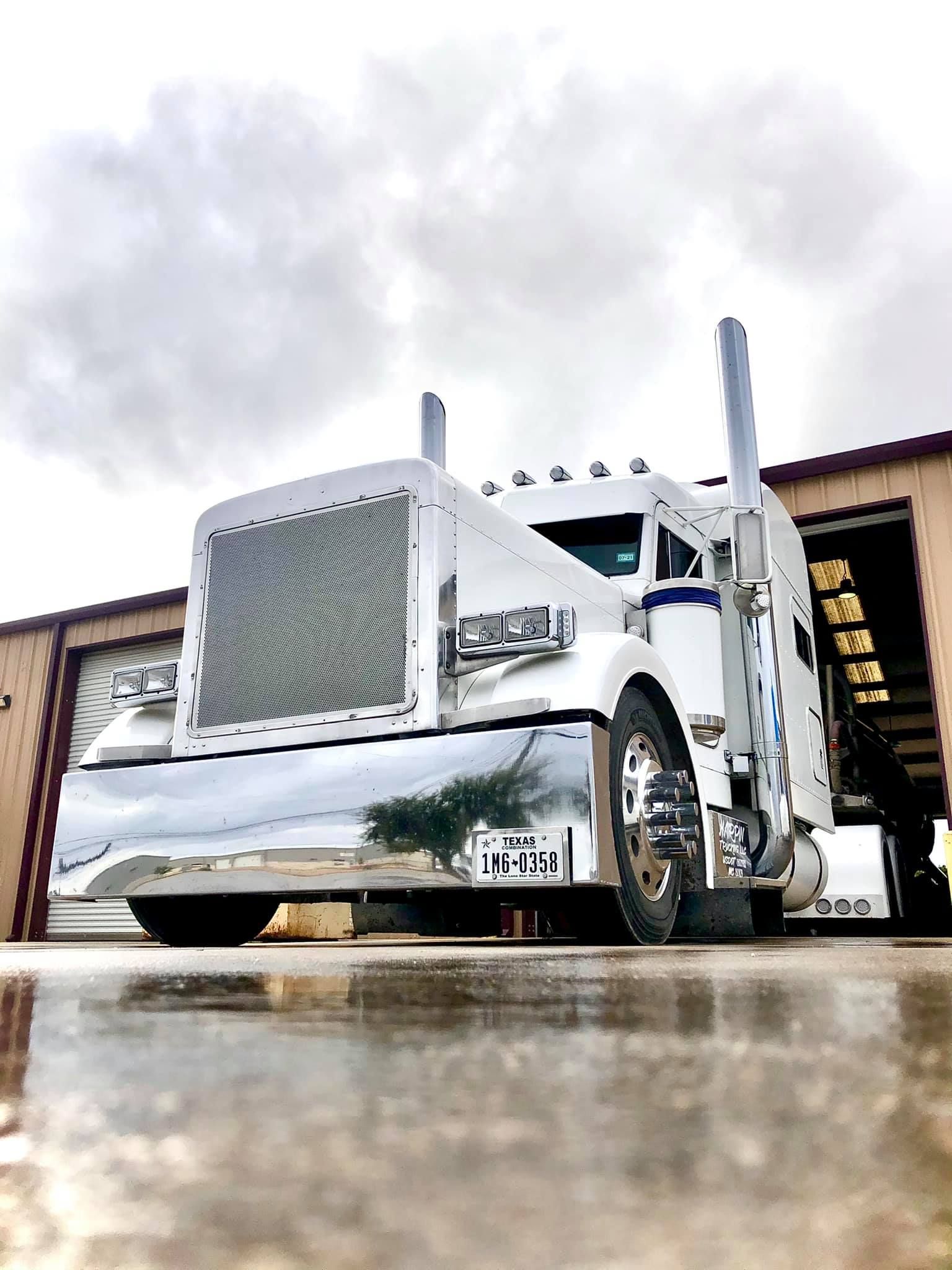 a white semi truck is parked in front of a building .