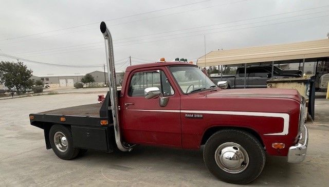 A red truck with a flat bed and an exhaust pipe is parked in a parking lot.