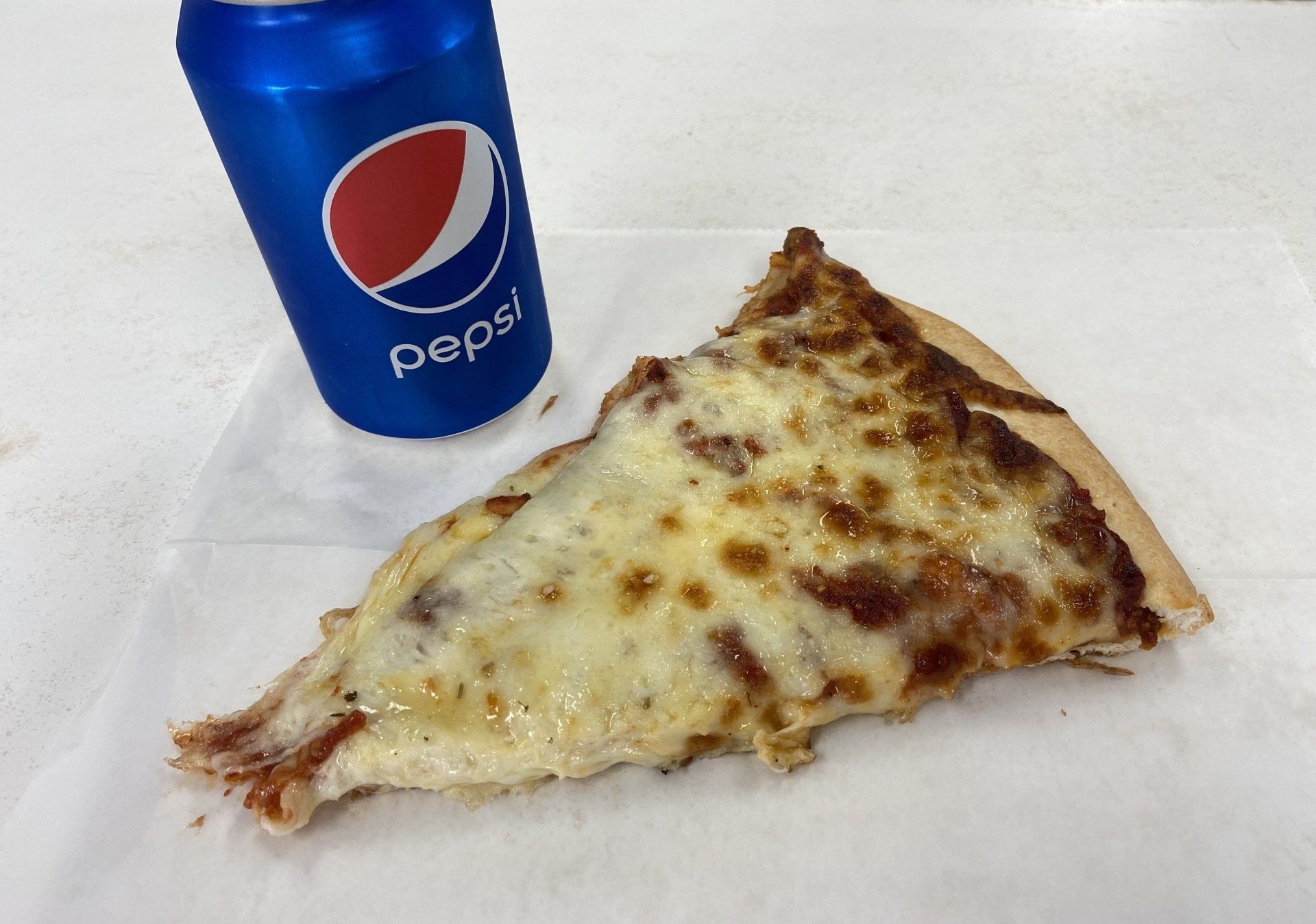Slice of cheesy pizza and a Pepsi can on a white paper.