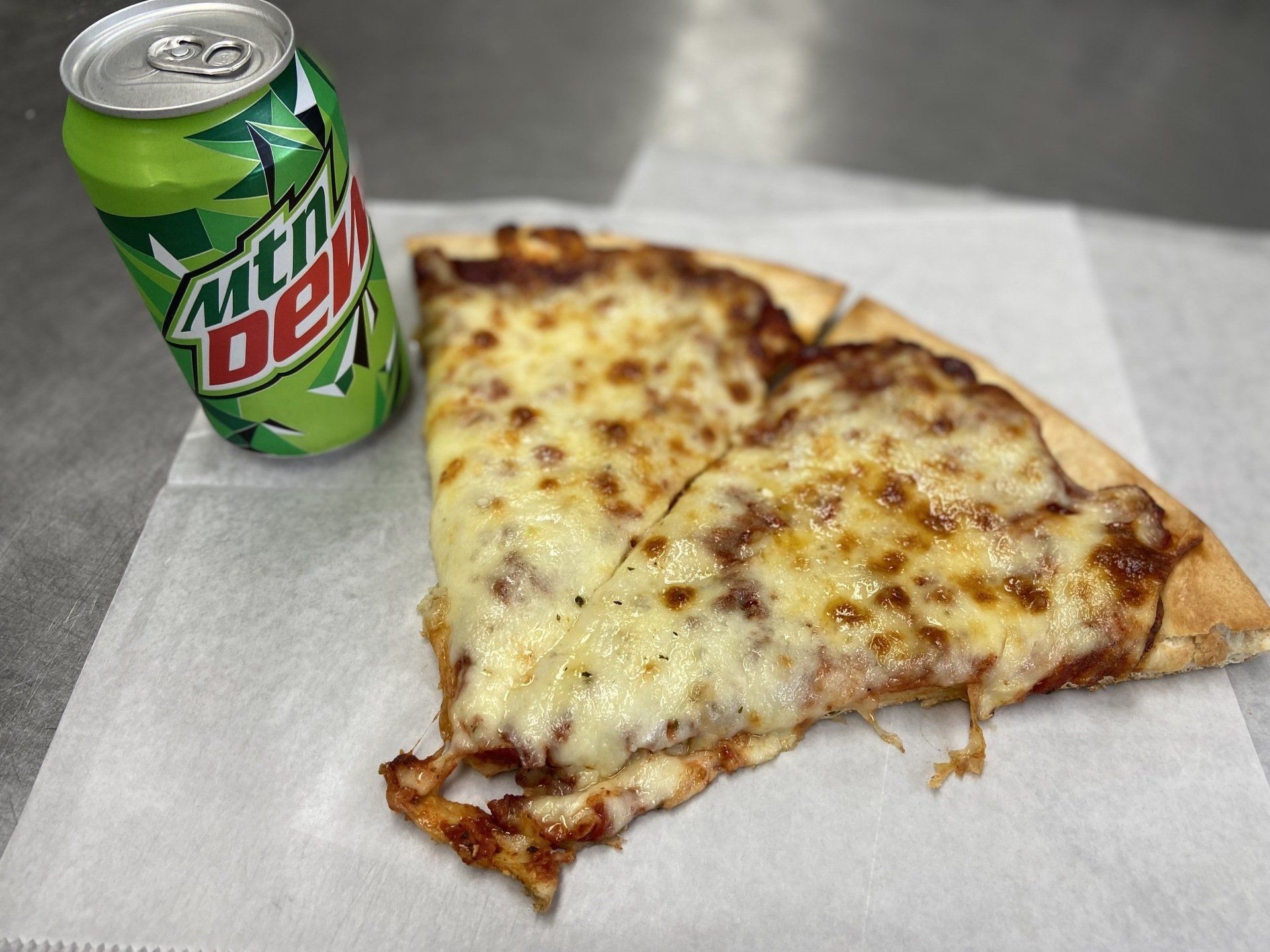 Pizza slice and a Mountain Dew can on a paper napkin.