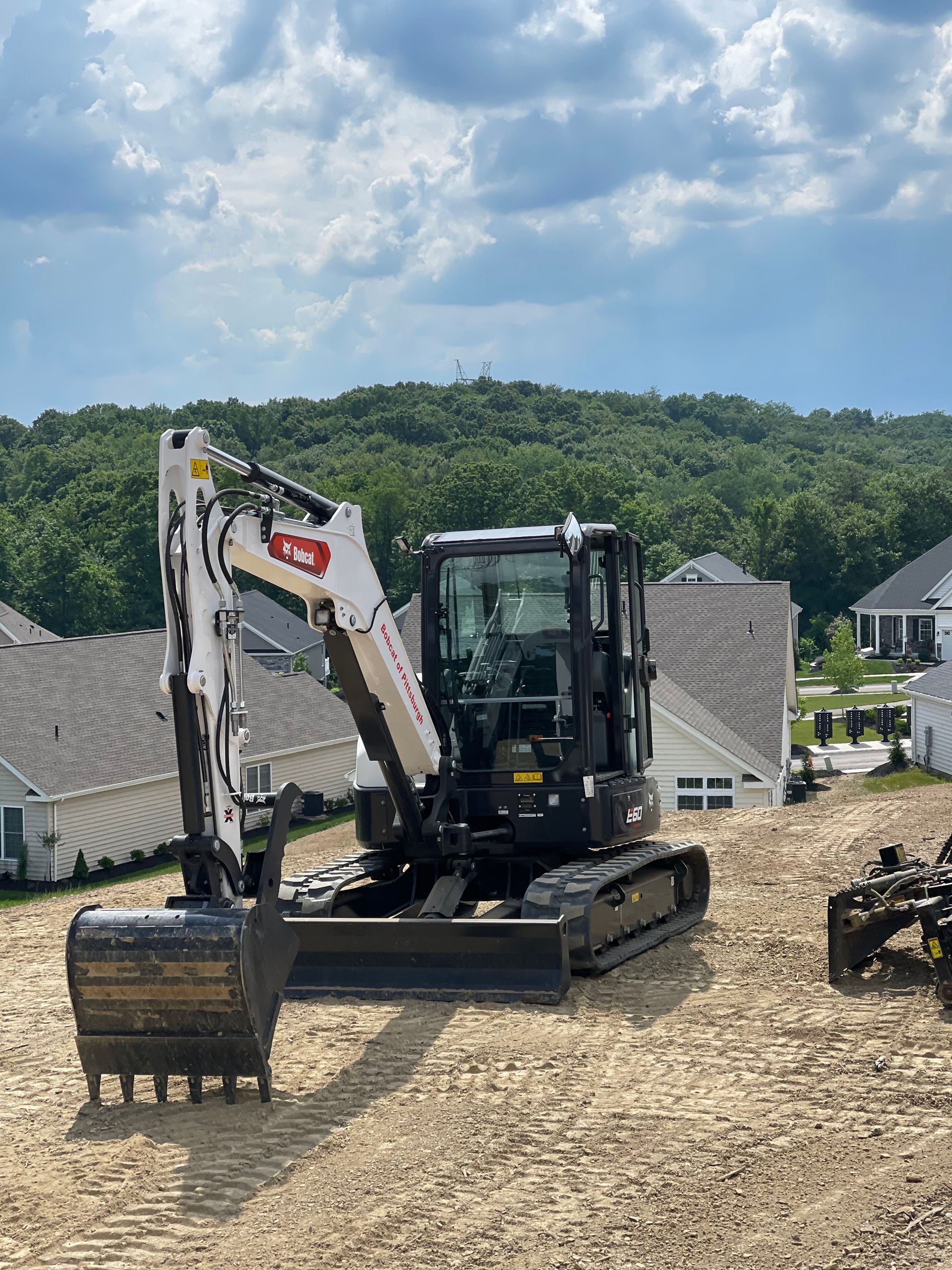 Bobcat excavator on a construction site, ready to dig. Sunny day with houses in the background.