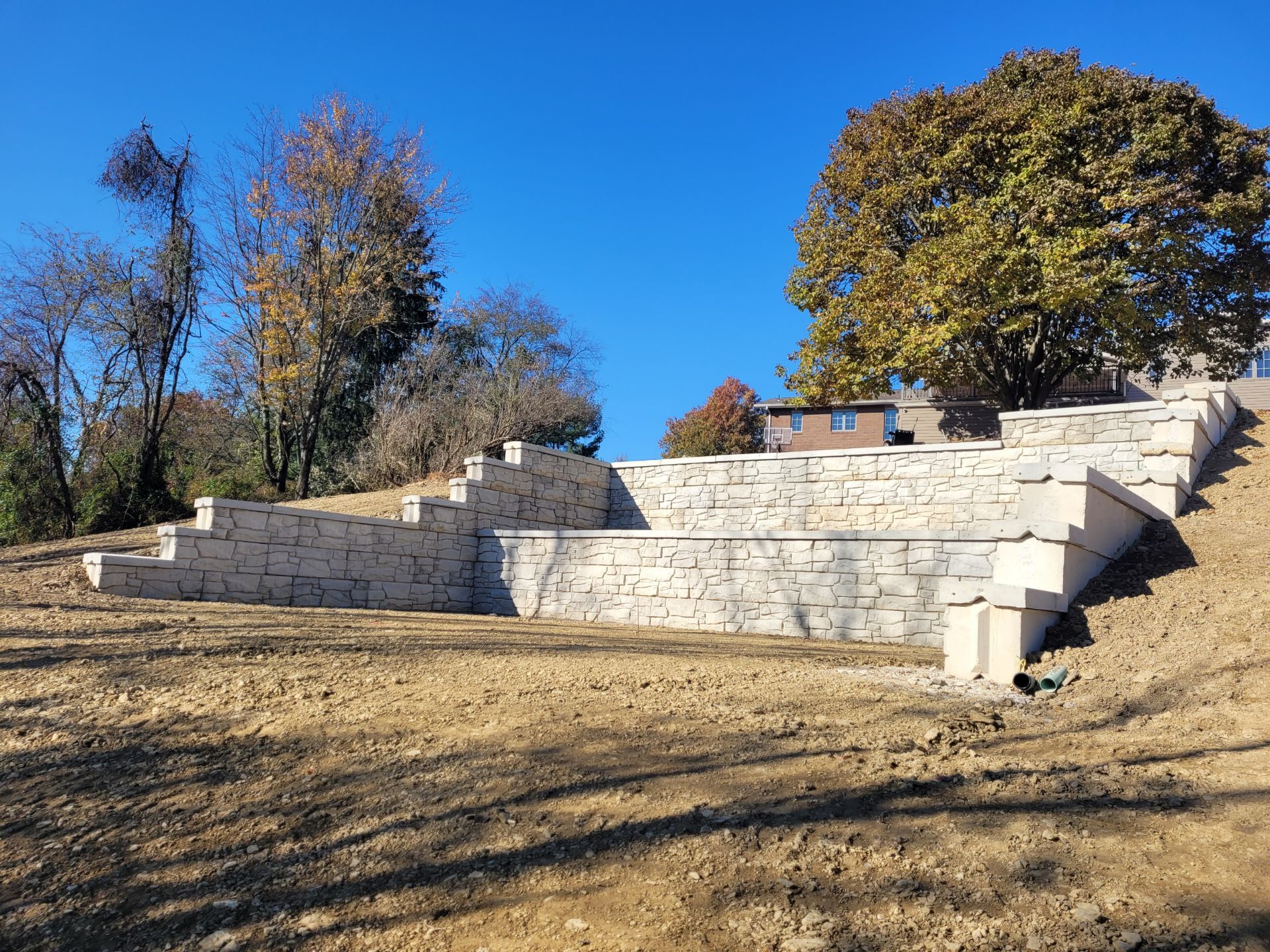 Stone tiered amphitheater built into a hillside, with trees and blue sky.