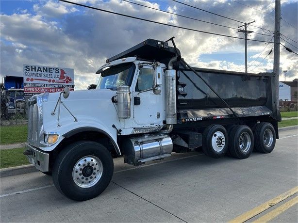 White dump truck parked on a paved road, under a cloudy sky.
