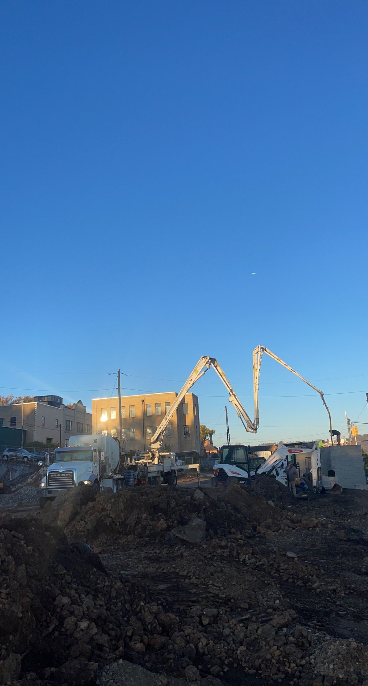 Construction site with concrete pump, blue sky.