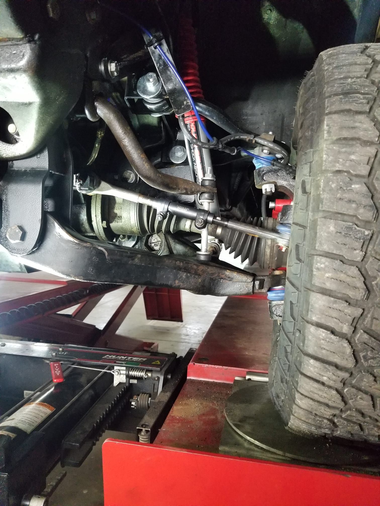 A close up of the underside of a car on a lift.