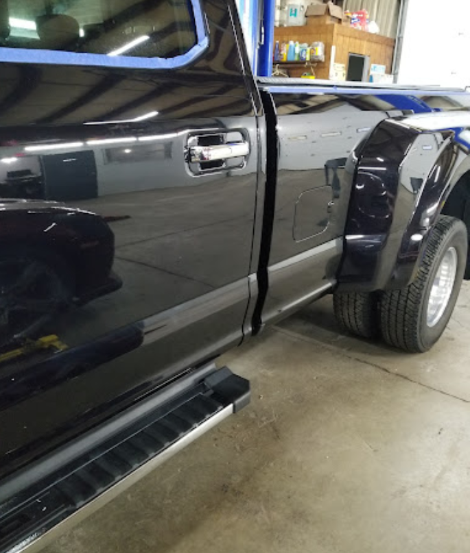 A black truck is parked in a garage with the door open