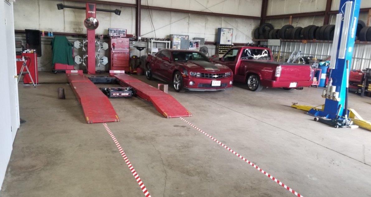 A red car is sitting on a lift in a garage.