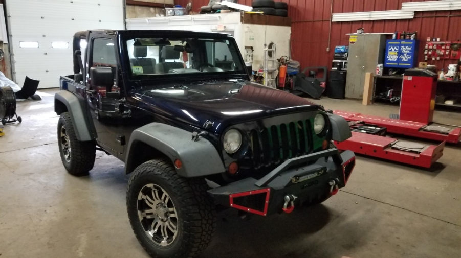 A black jeep is parked in a garage.