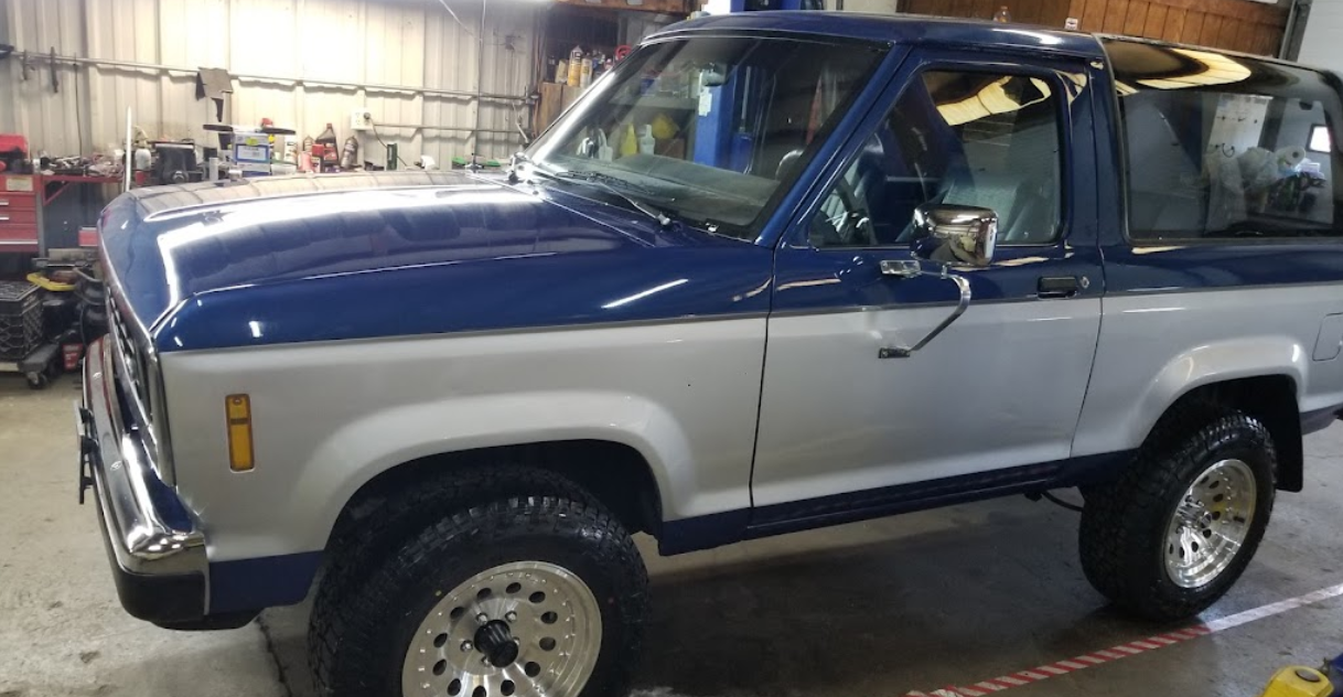 A blue and white truck is parked in a garage.