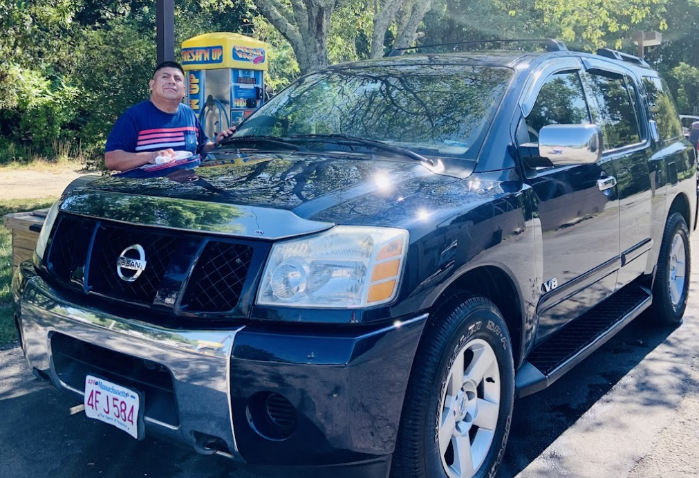 A man is standing in front of a black Nissan Titan SUV.