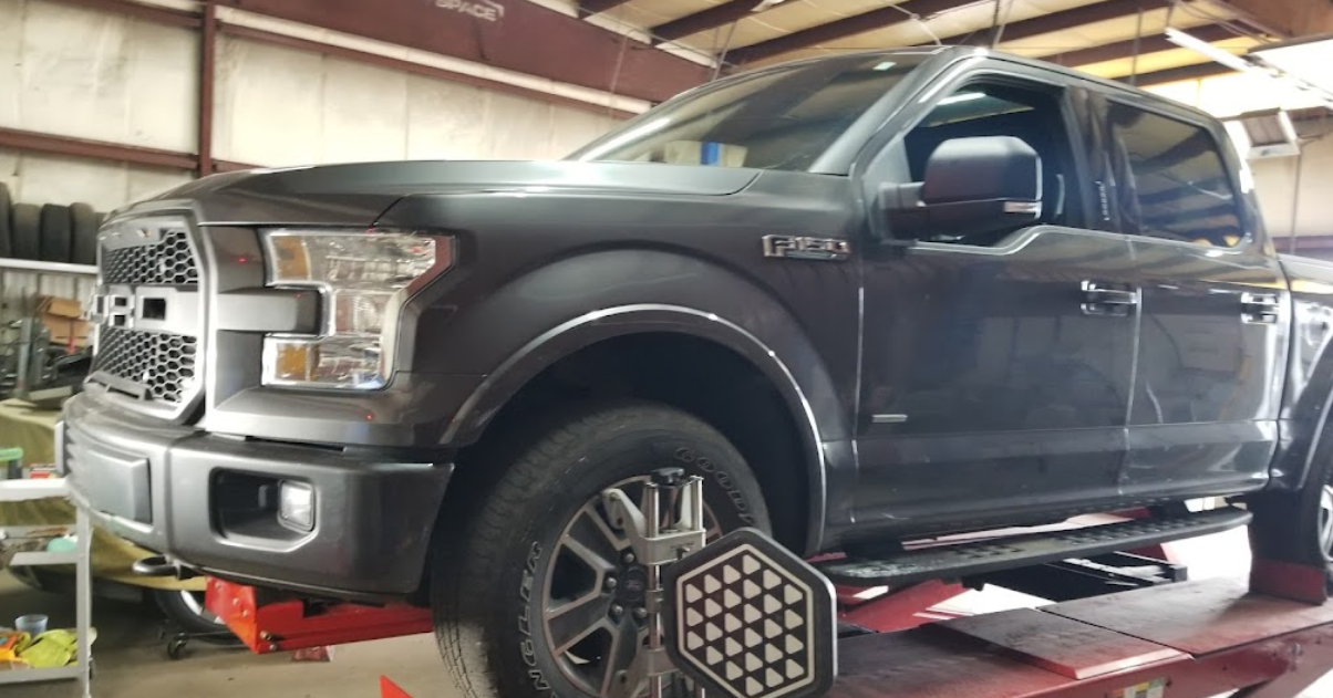 A truck is sitting on a lift in a garage.