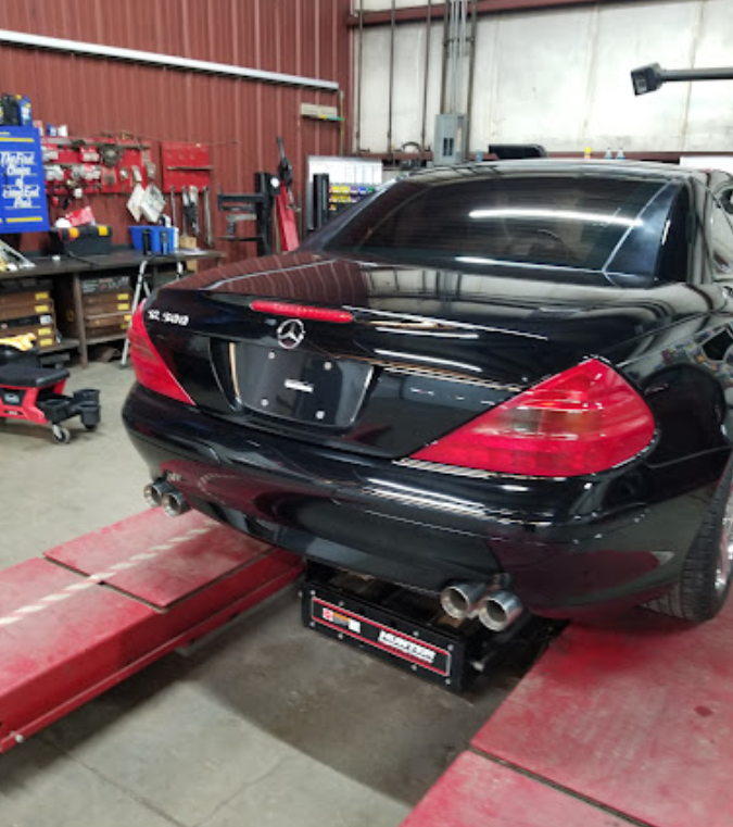 A black mercedes is on a lift in a garage