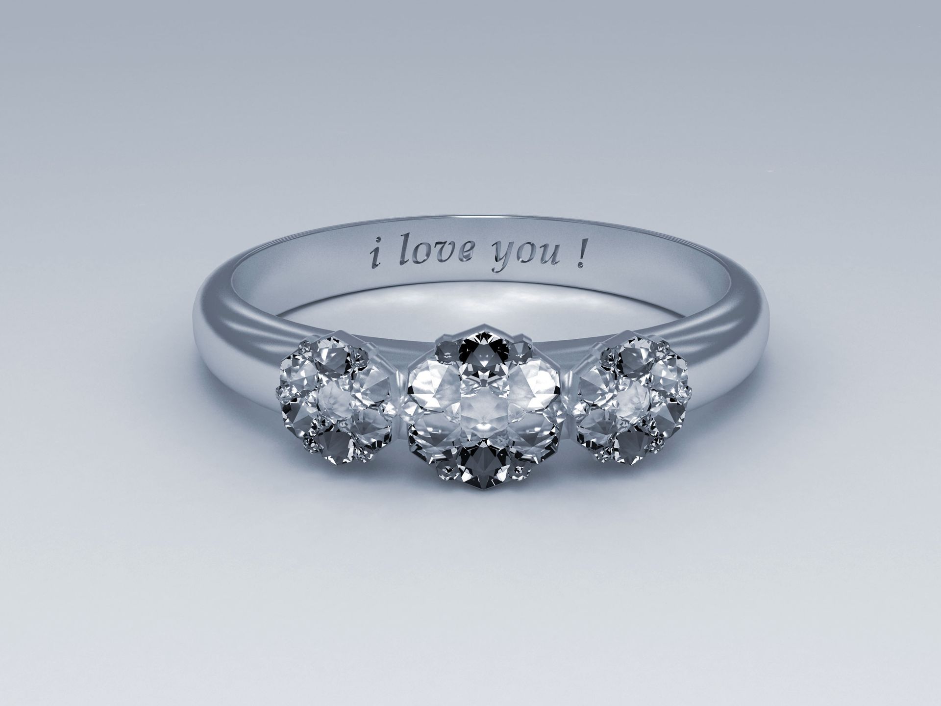 Silver diamond ring engraved “i love you!” on a light gray background
