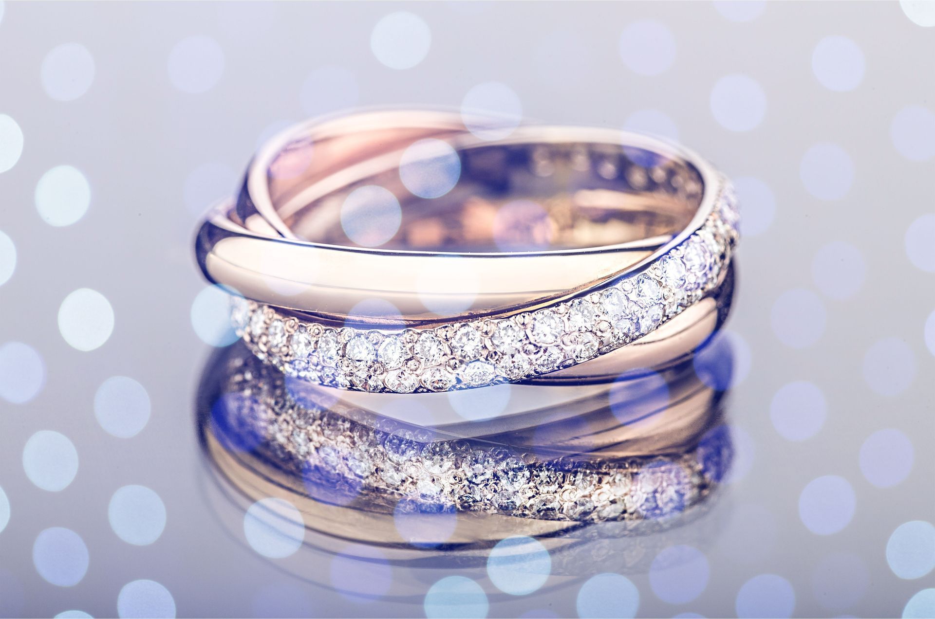 Stacked diamond wedding bands on a soft blue reflective background