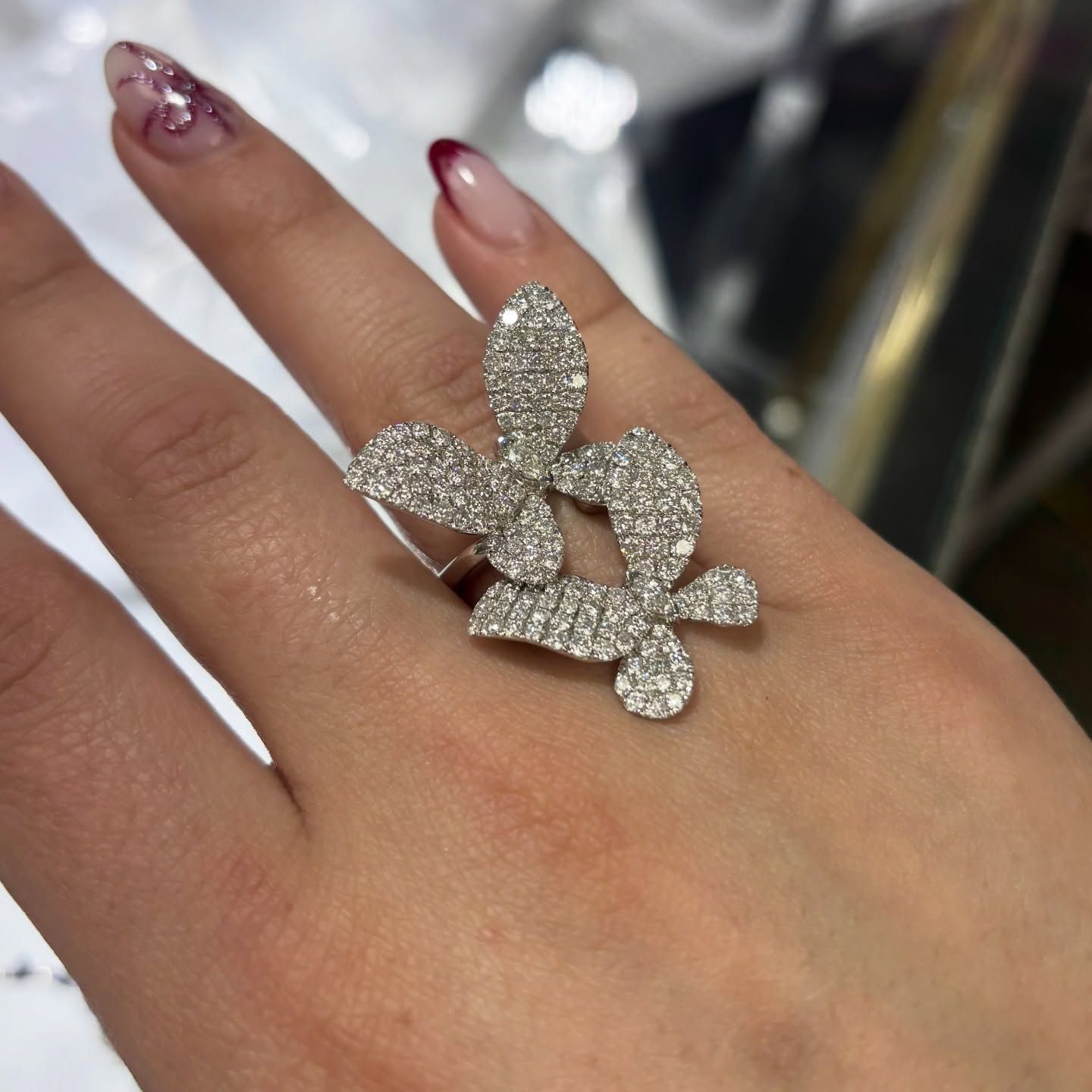 Hand wearing a sparkling butterfly-shaped ring with a dangling floral charm