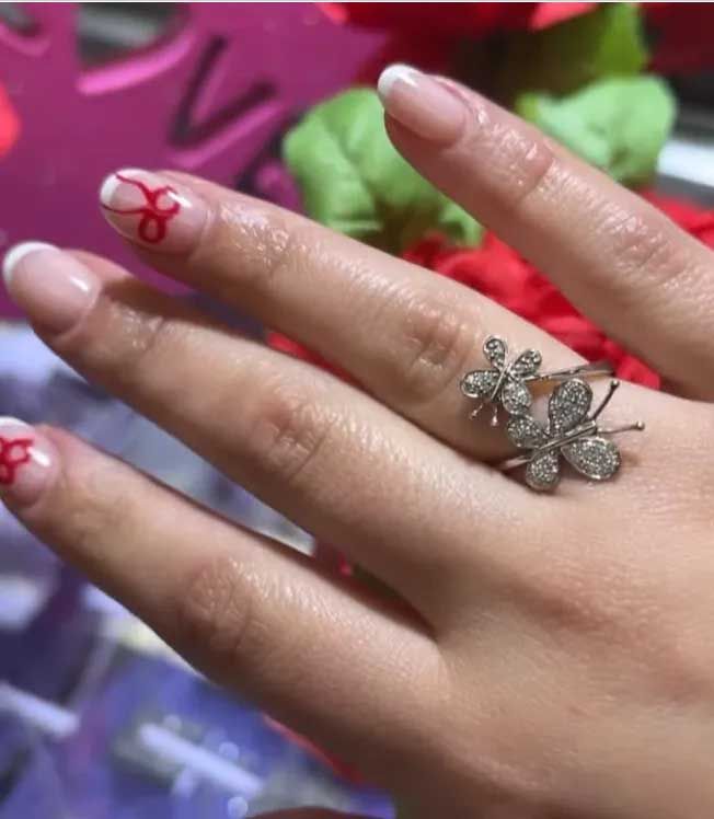 Hand with red nail art wearing a silver flower ring