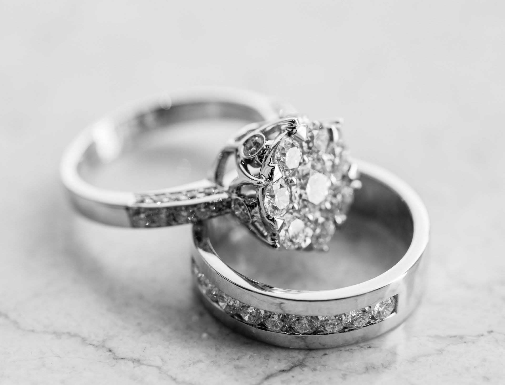 Two silver rings with a diamond cluster on a light marble surface