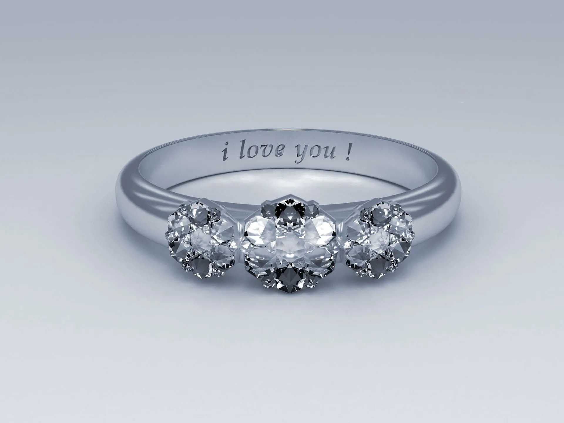 Silver engagement ring with three diamond stones and “i love you!” engraved inside the band