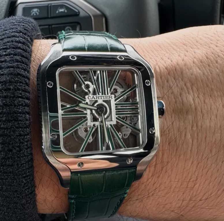Close-up of a wrist wearing a Cartier square watch with a green leather strap